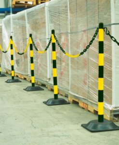 Diverse paletti gialli nero con catena in fila per delimitare una zona in un magazzino